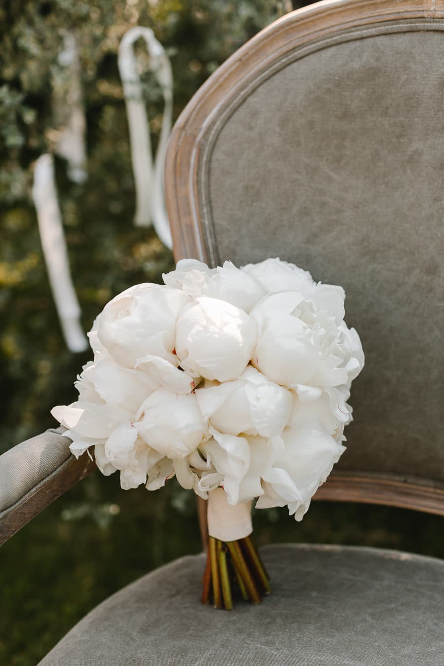 Bouquet of white peonies resting on a grey velvet chair