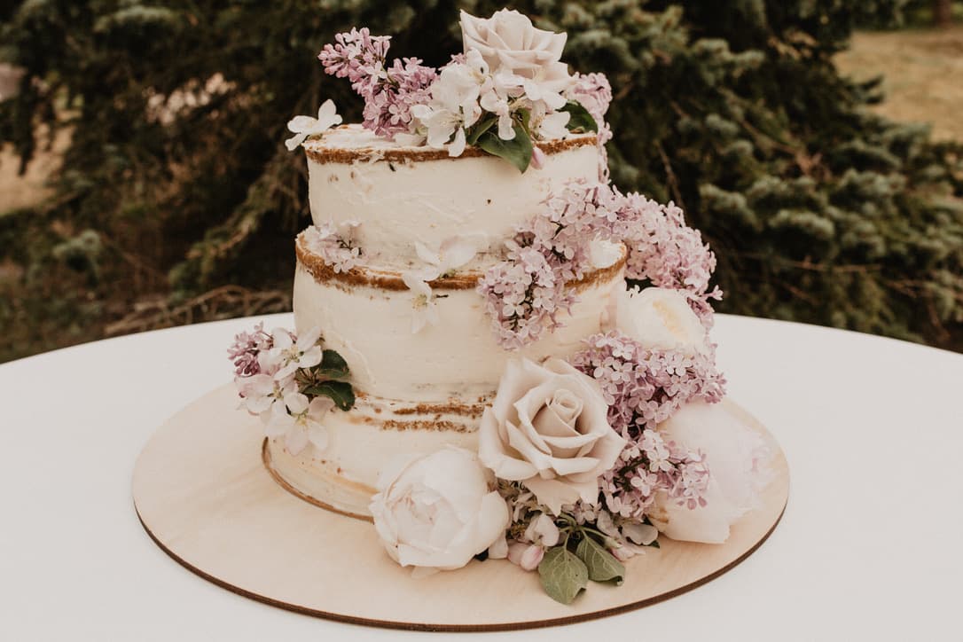 Two-tier semi-naked cake dressed with lilac, roses and peonies