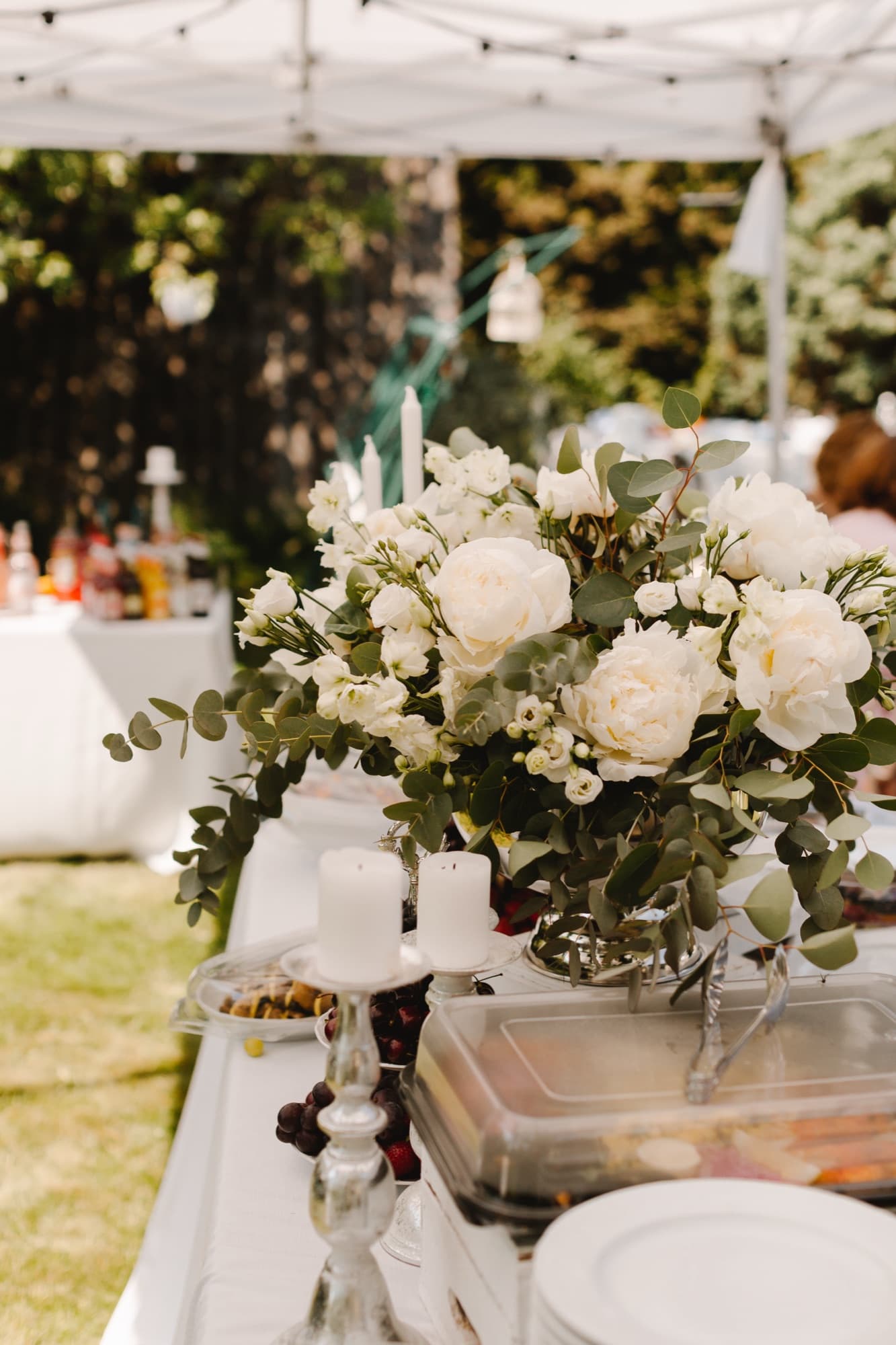 White rose and eucalyptus centrepiece on a long outdoor dining table