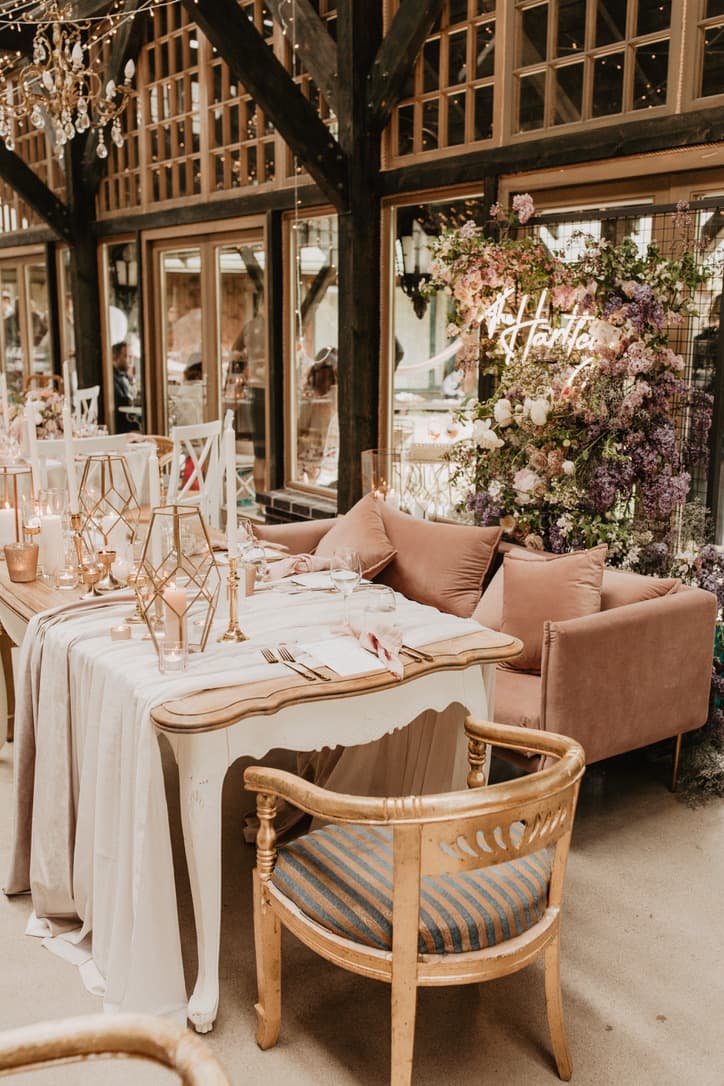 Outdoor lounge with a blush velvet sofa, lanterns and a floral wall